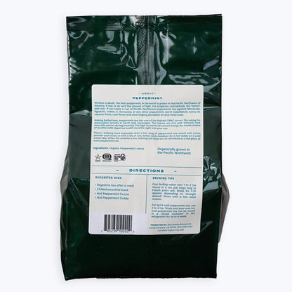 A dark green bag with a light tan back label with information about peppermint, suggested uses, and brewing tips on how to make peppermint tea. 